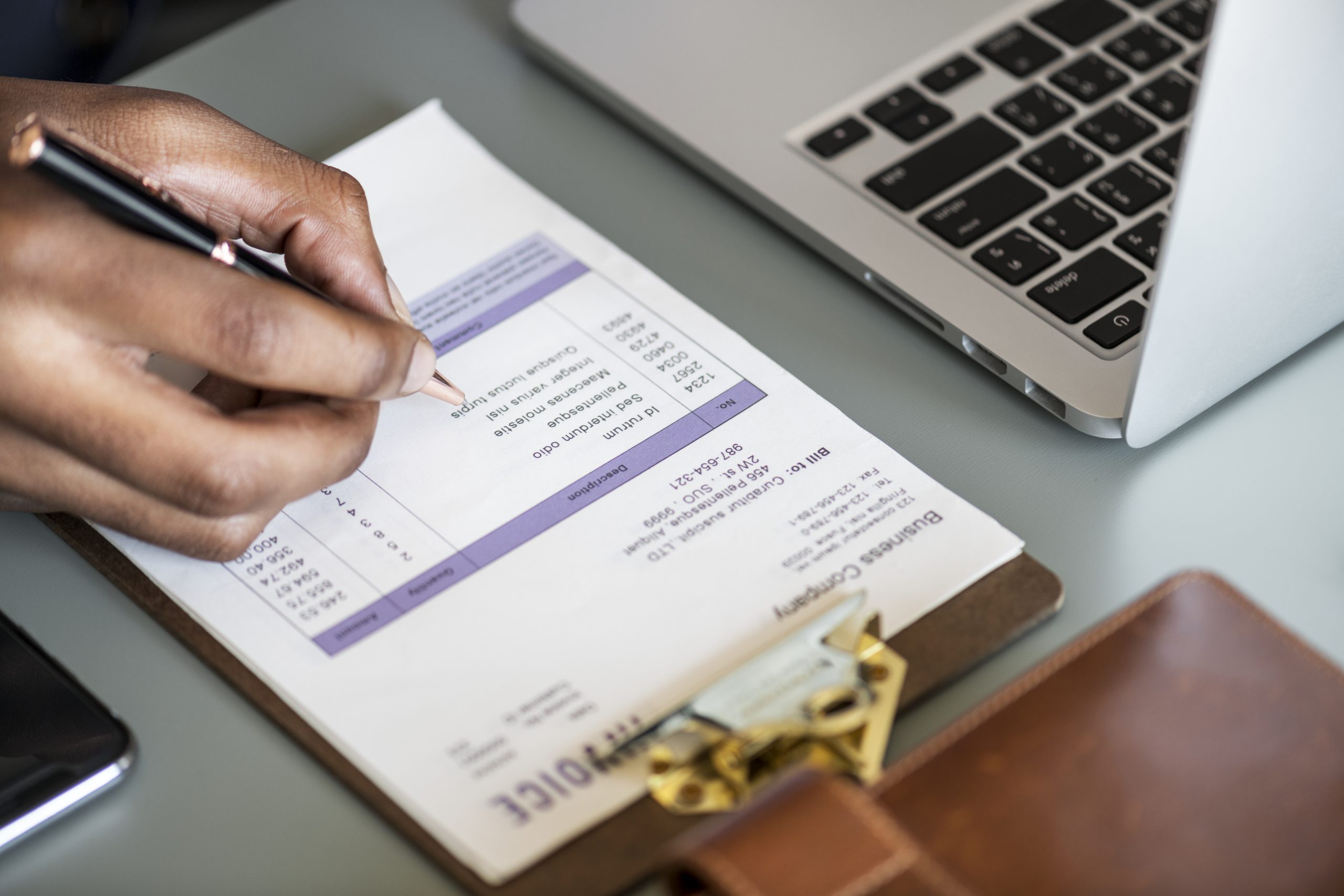 Person reviewing a tax invoice beside a laptop